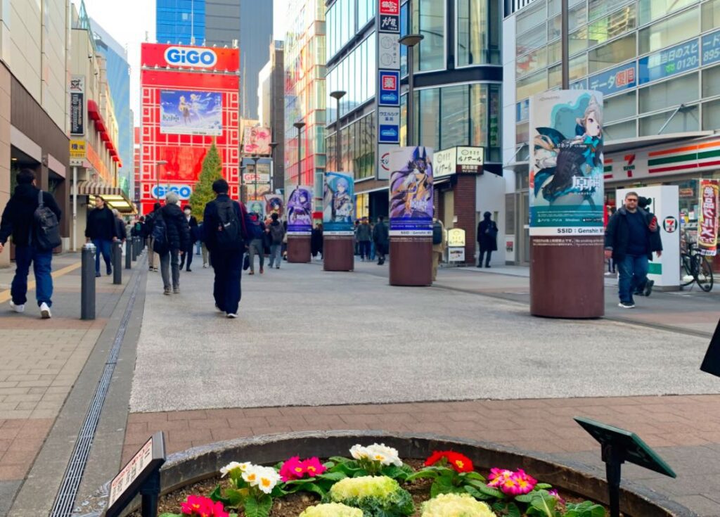 Vibrant street view of Akihabara, showcasing colorful billboards and bustling pedestrian activity, highlighting the lively atmosphere of Tokyo's tech and anime district.