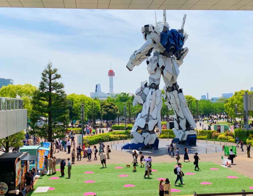 Odaiba’s iconic life-size Unicorn Gundam statue at DiverCity Tokyo Plaza, surrounded by lush greenery and a bustling plaza, capturing the district’s futuristic vibe.