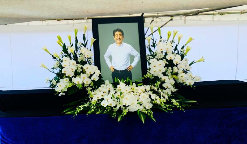 A memorial altar with a framed photograph of former Japanese Prime Minister Shinzo Abe, surrounded by white flowers, during his funeral ceremony at Zojoji Temple in Tokyo, Japan.